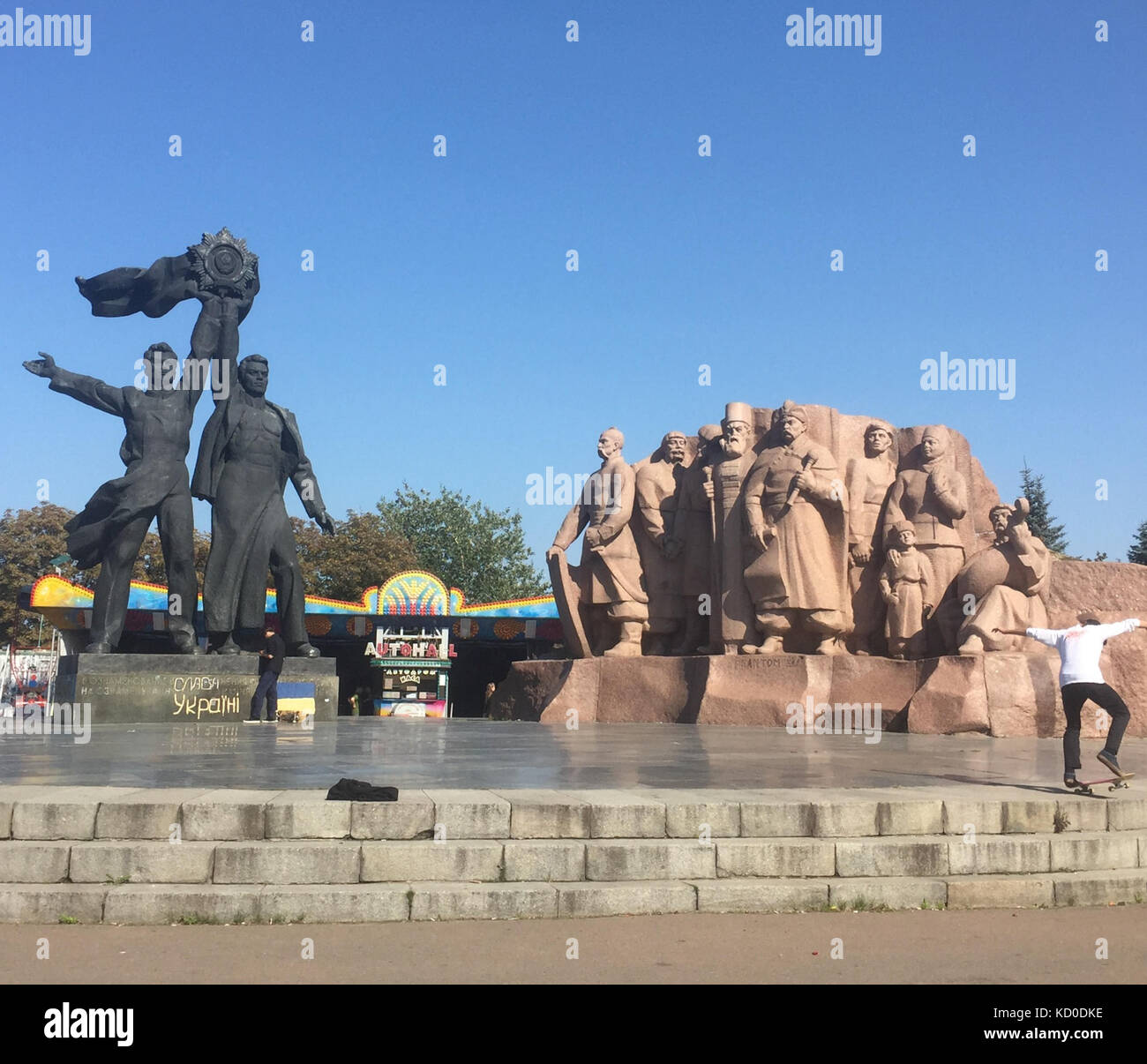 Les pratiques d'un skateur professionnel devant les statues de héros de l'ukraine au rainbow arch, Kiev, Ukraine Banque D'Images