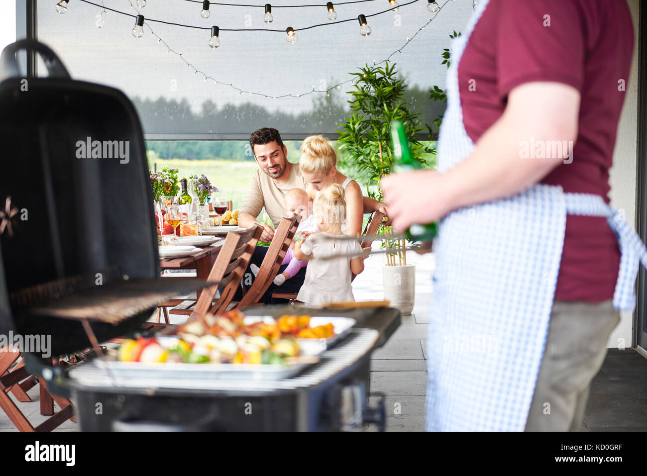 Man barbecuing at déjeuners en famille on patio Banque D'Images