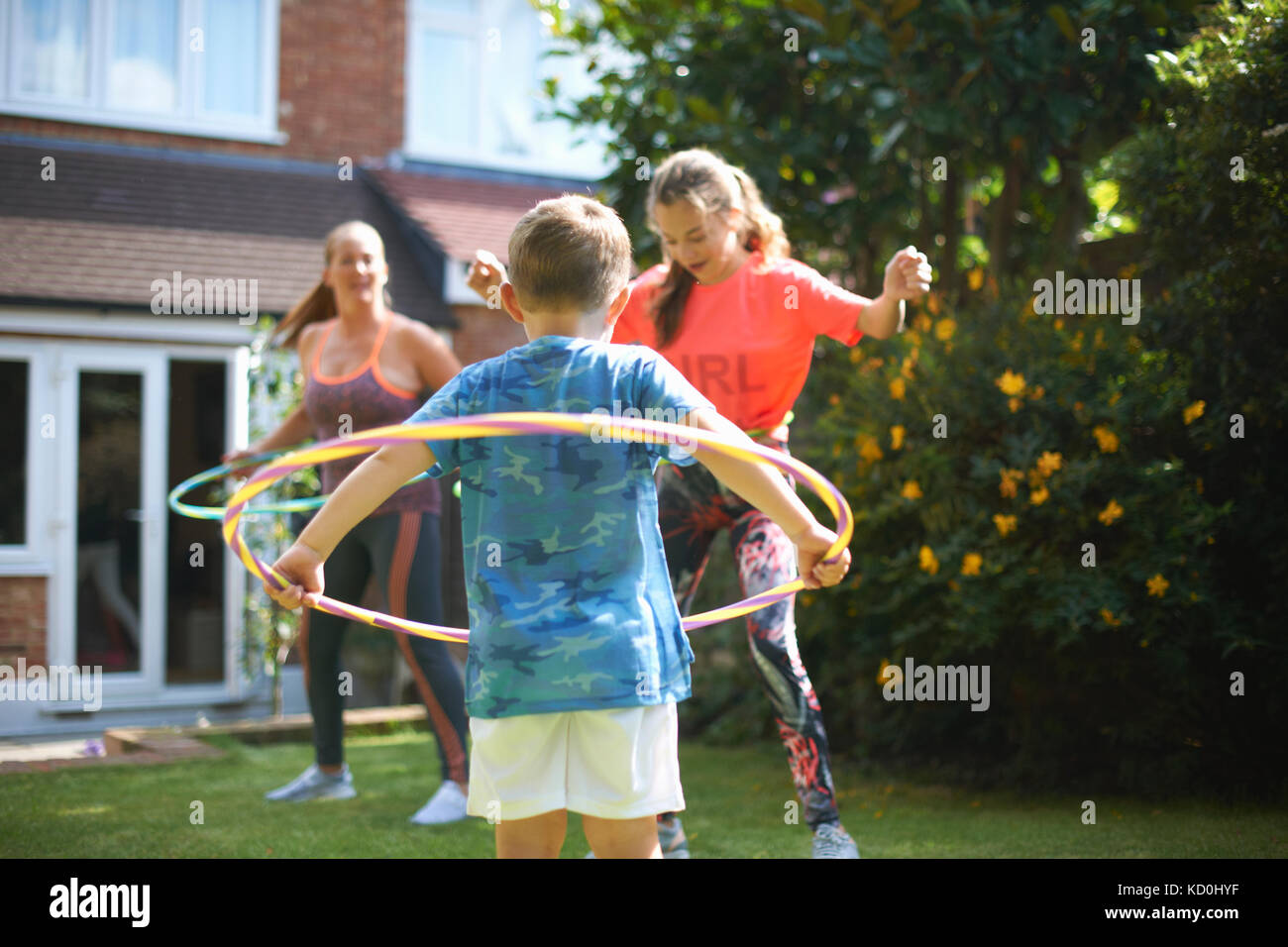 Femme mature avec fils et fille adolescente hula hooping in garden Banque D'Images