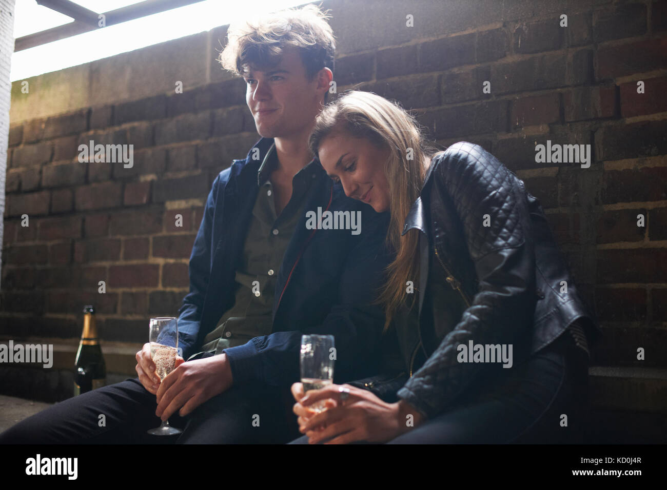 Young couple sitting in abri bus avec prosecco Banque D'Images