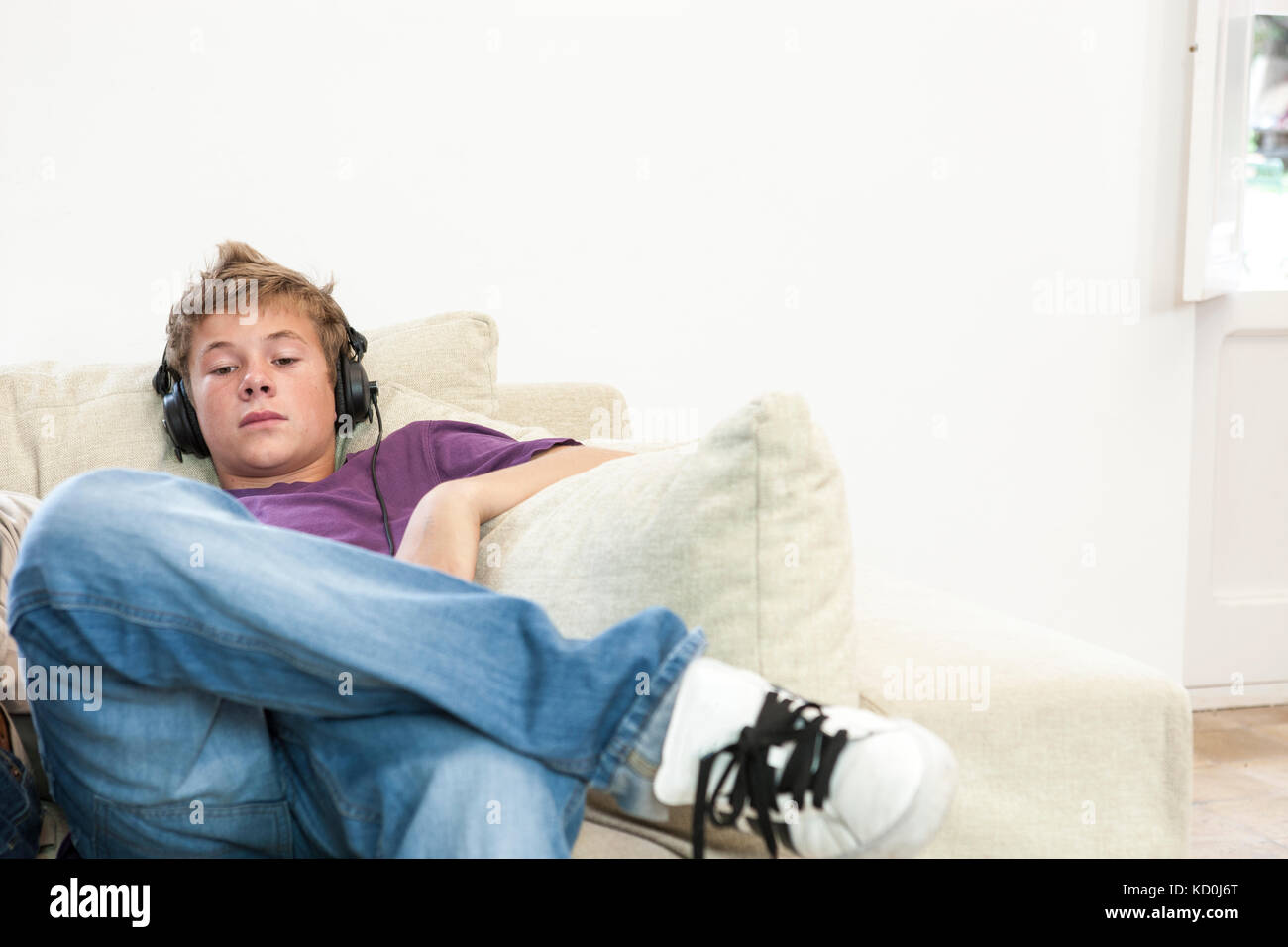 Teenage boy sitting on sofa à écouter la musique de casque Banque D'Images