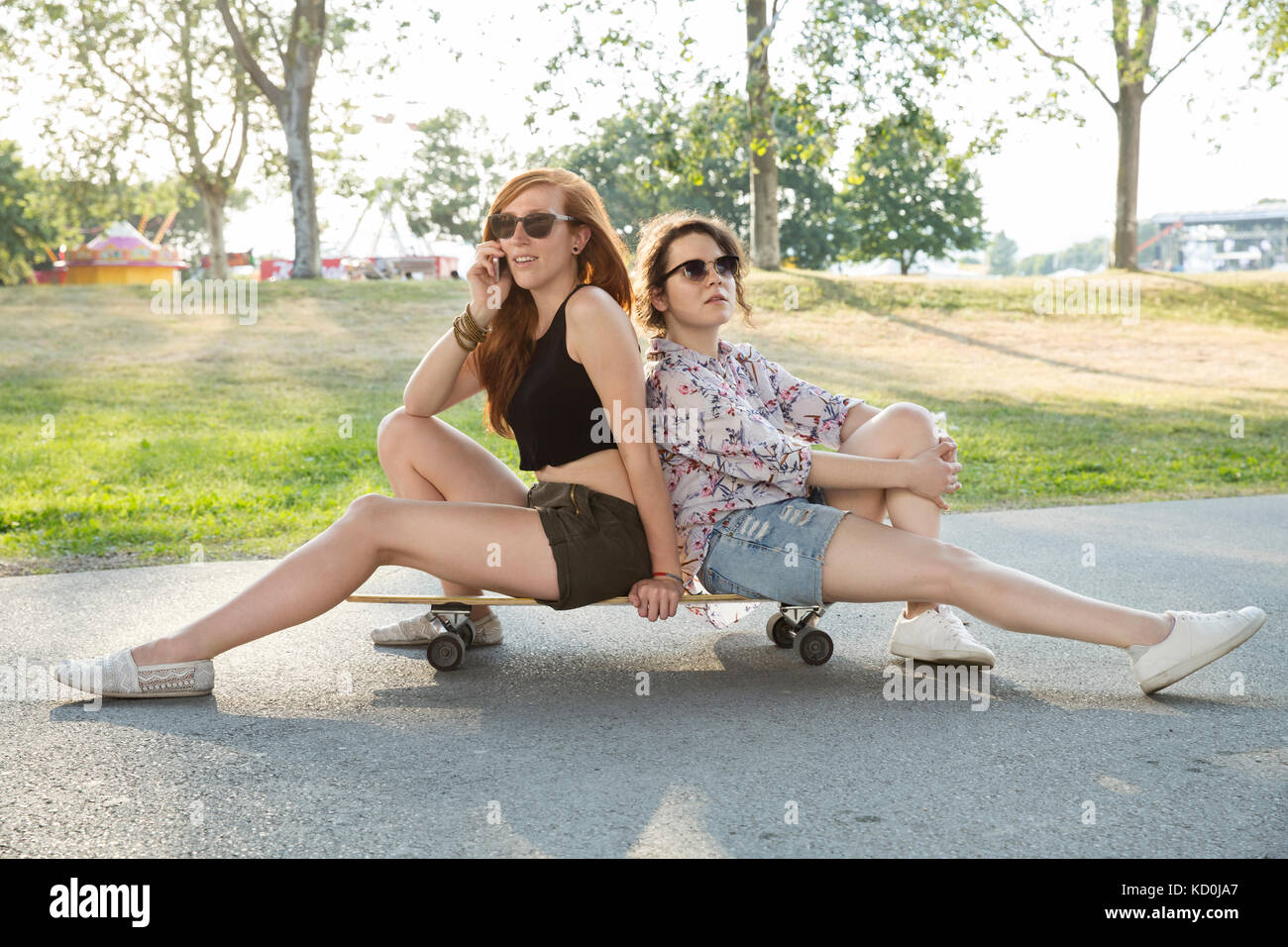 Portrait de deux jeunes femmes à l'extérieur, assis sur planche Banque D'Images