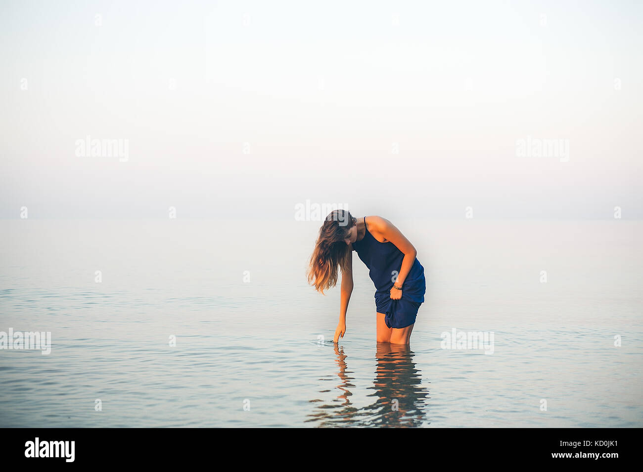 Jeune femme genou profondément en touchant la surface de la mer, Odessa, Ukraine Banque D'Images