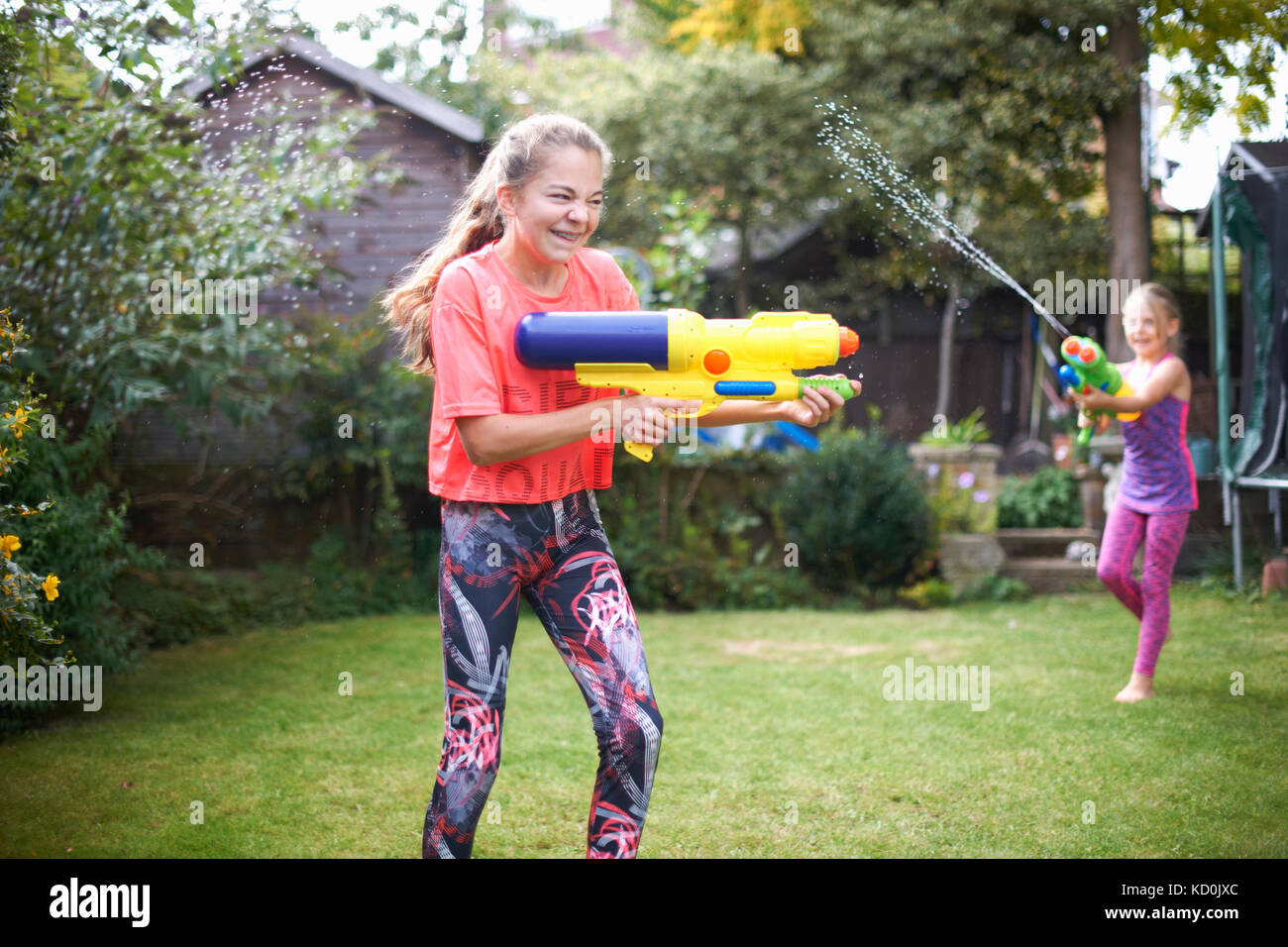 Adolescente et sa sœur d'avoir de l'eau lutte des armes à feu dans le jardin Banque D'Images