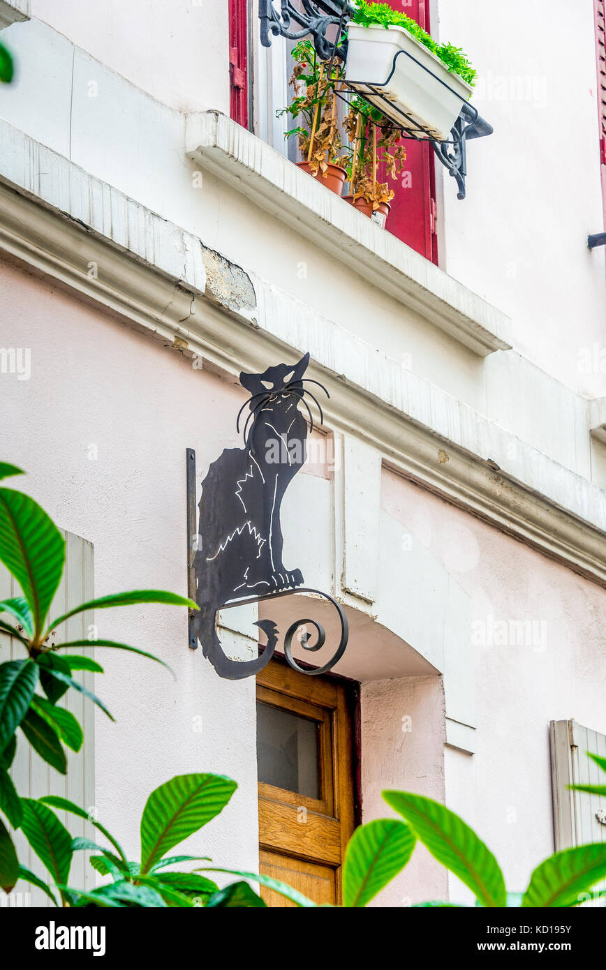 Un chat noir est assis au-dessus d'une maison sur la rue colorée Crémieux à Paris, France Banque D'Images
