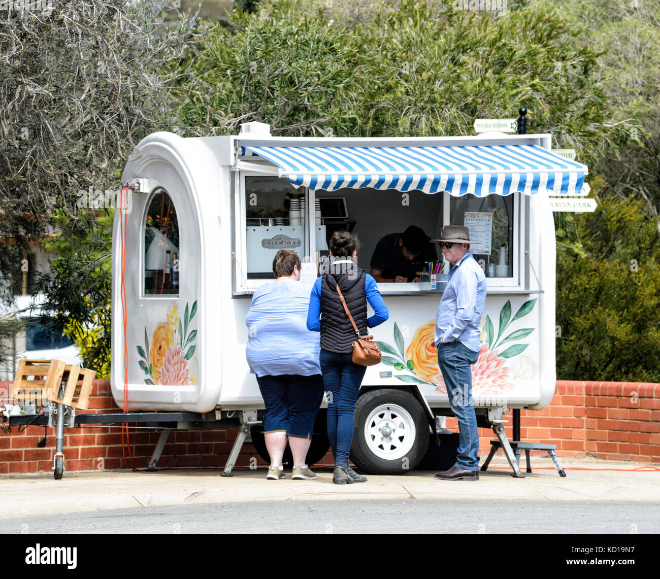 Trois personnes la queue pour acheter un café d'un charmant café mobile van, dans la petite ville rurale de Lockhart, New South Wales, NSW, Australie Banque D'Images