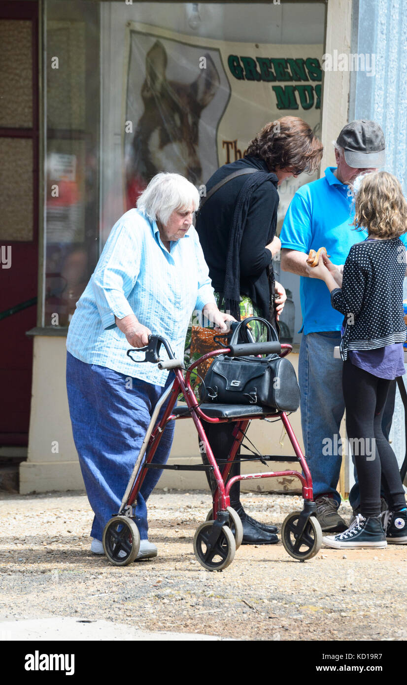 Femme âgée à l'aide d'un déambulateur ou walker siège dans la rue Banque D'Images