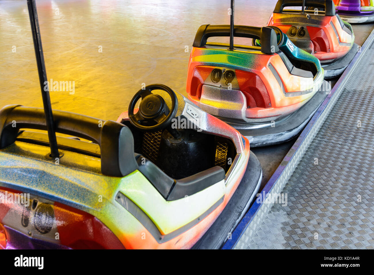 Dodgem colorés voitures alignées sur le côté de la piste en attente d'enfants dans une fête foraine. Banque D'Images