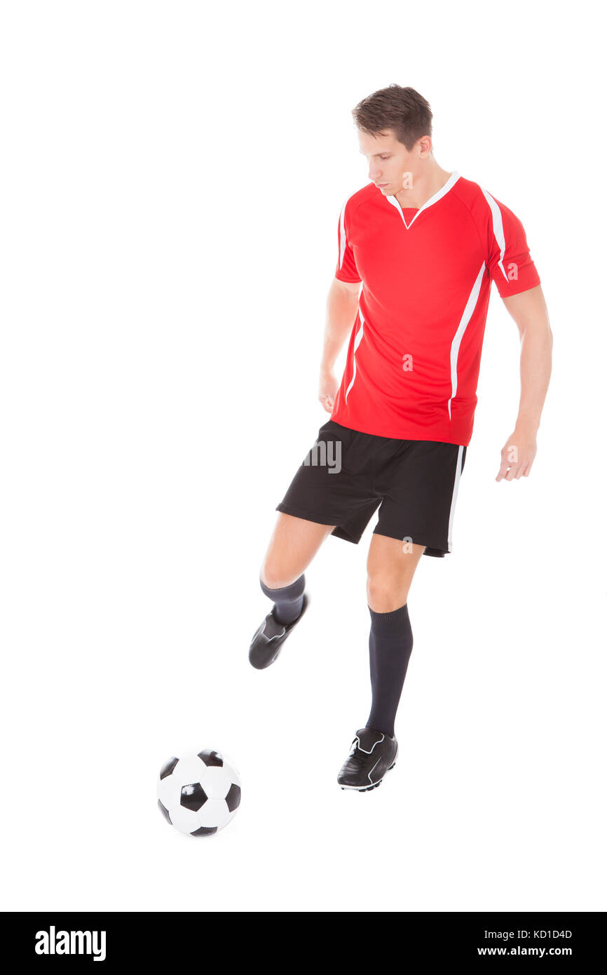 Portrait of young male soccer player kicking football Banque D'Images