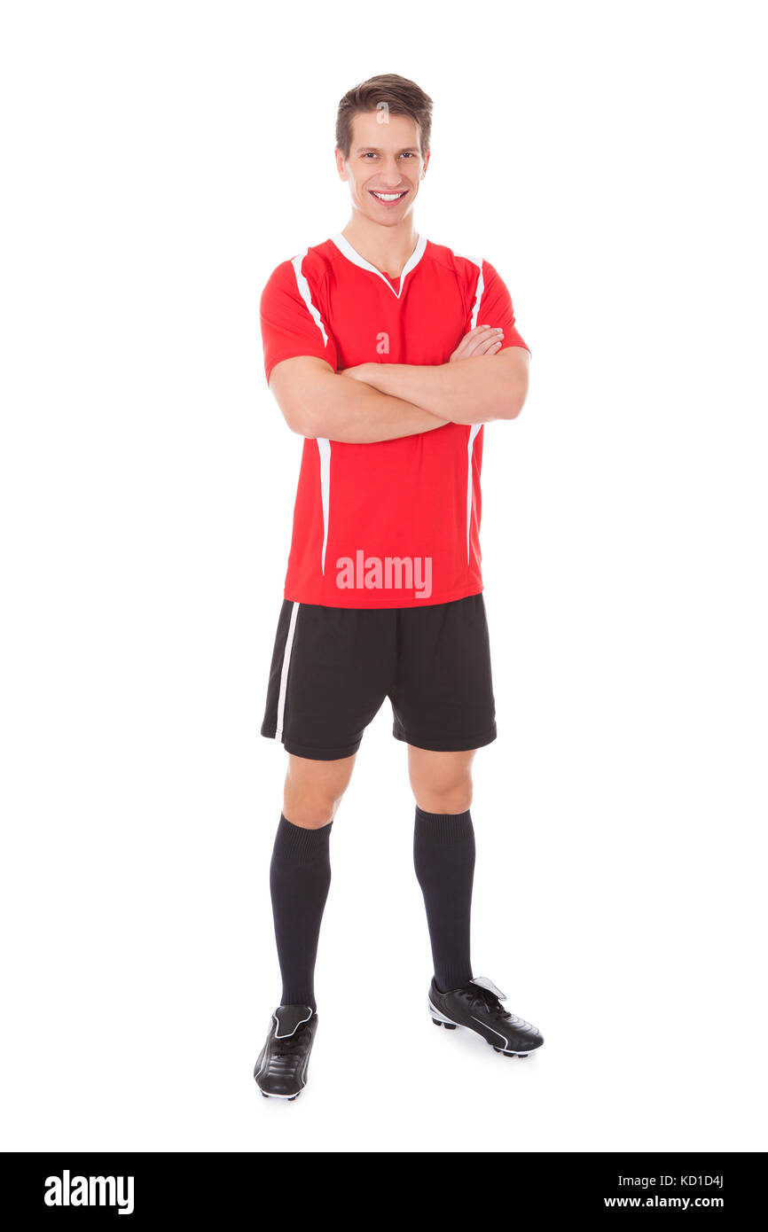 Certain joueur de foot avec bras croisés sur fond blanc Banque D'Images