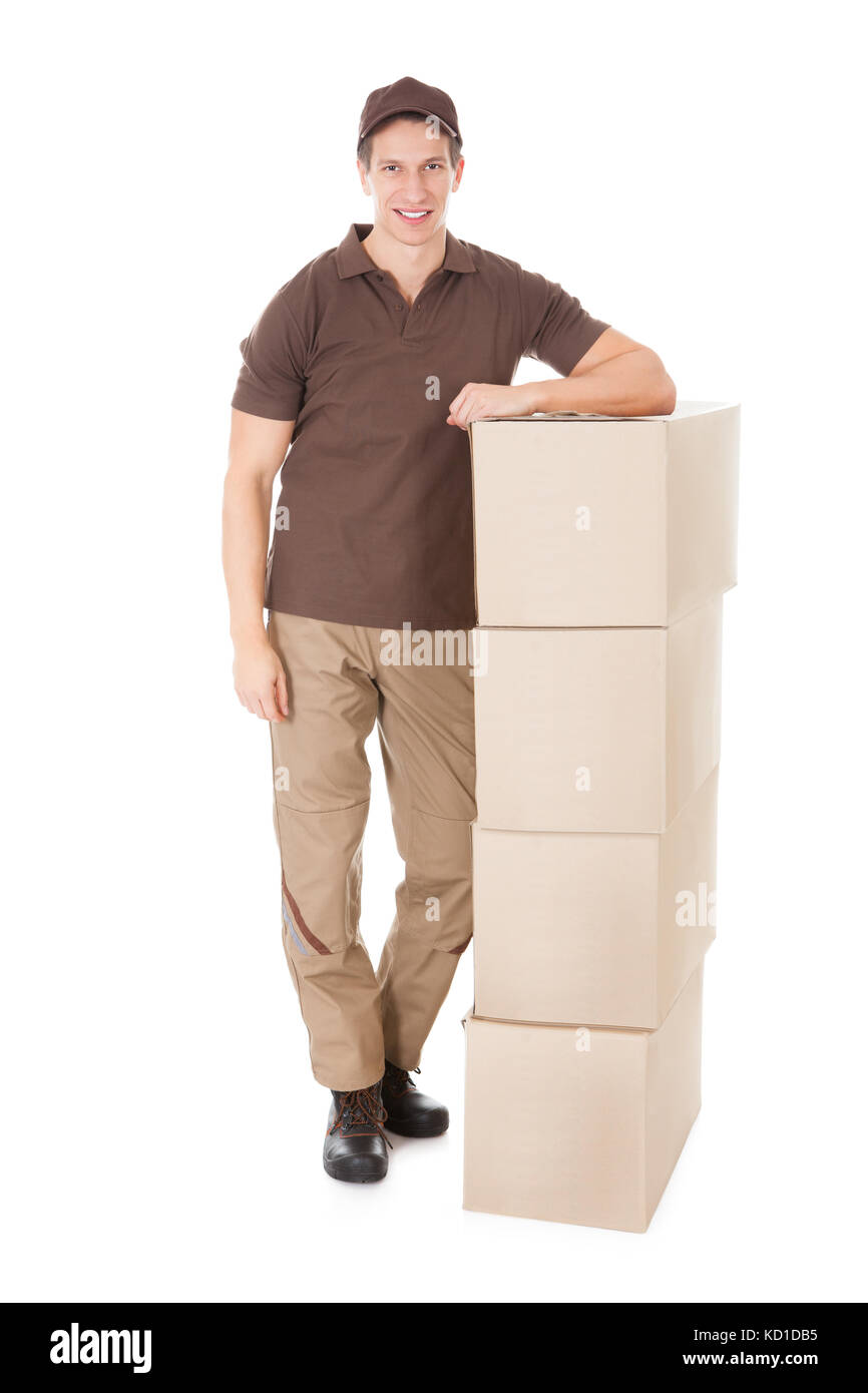 Young Delivery Man sur une pile de boîtes sur fond blanc Banque D'Images