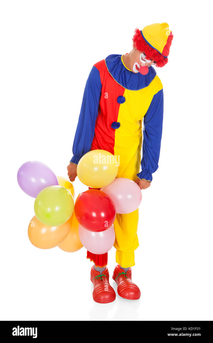 Portrait d'un clown triste avec des ballons multicolores sur fond blanc Banque D'Images