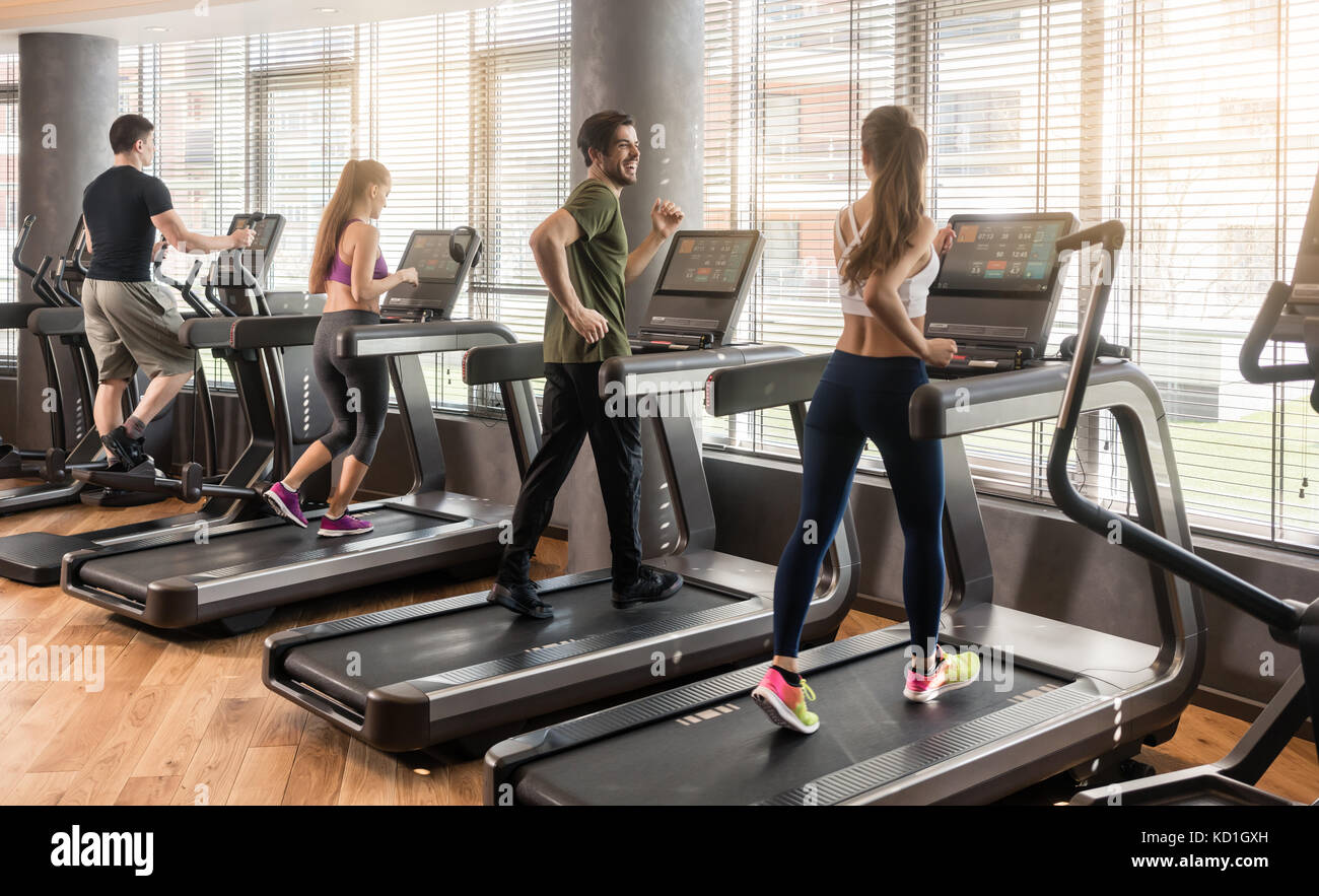 Groupe de quatre personnes courant sur des tapis roulants dans fitness gym Banque D'Images