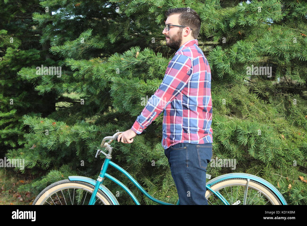 Un homme et le modèle vêtu d'un Chemise à carreaux en flanelle bleu jeans avec des manèges et pose avec un vélo vintage/location dans le pays Banque D'Images