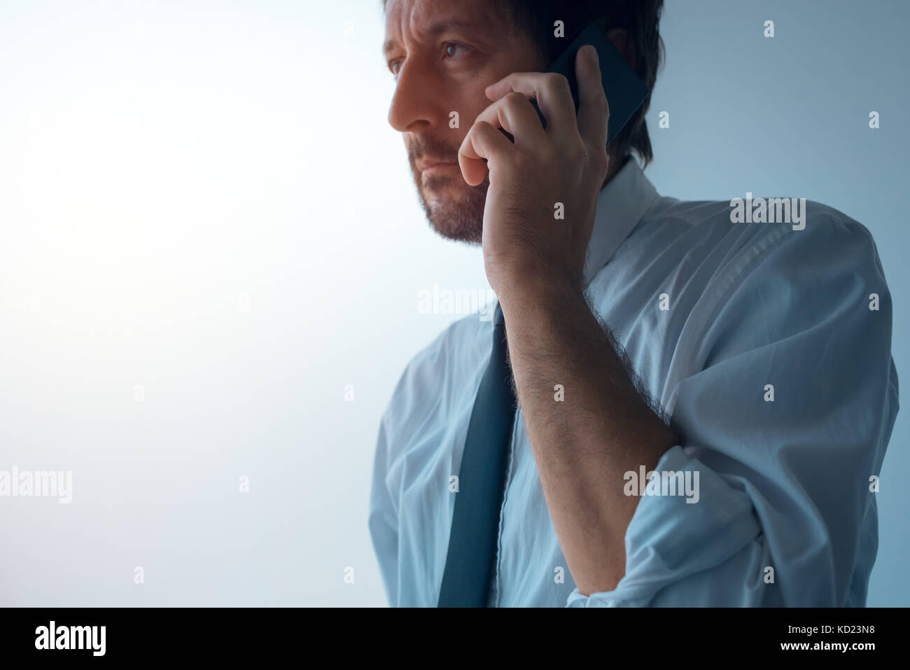 Businessman standing next to office de fenêtre et talking on mobile phone. des profils caucasian business personne à l'aide d'application pour smartphone pour communiquer avec l'équipe Banque D'Images