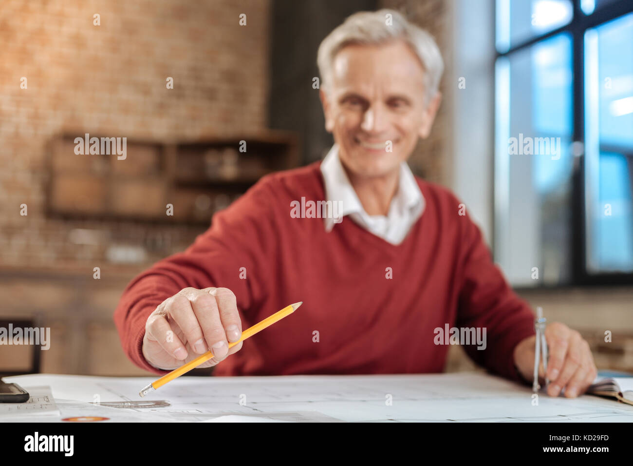 Ingénieur en souriant tout en travaillant au crayon sur le plan Banque D'Images