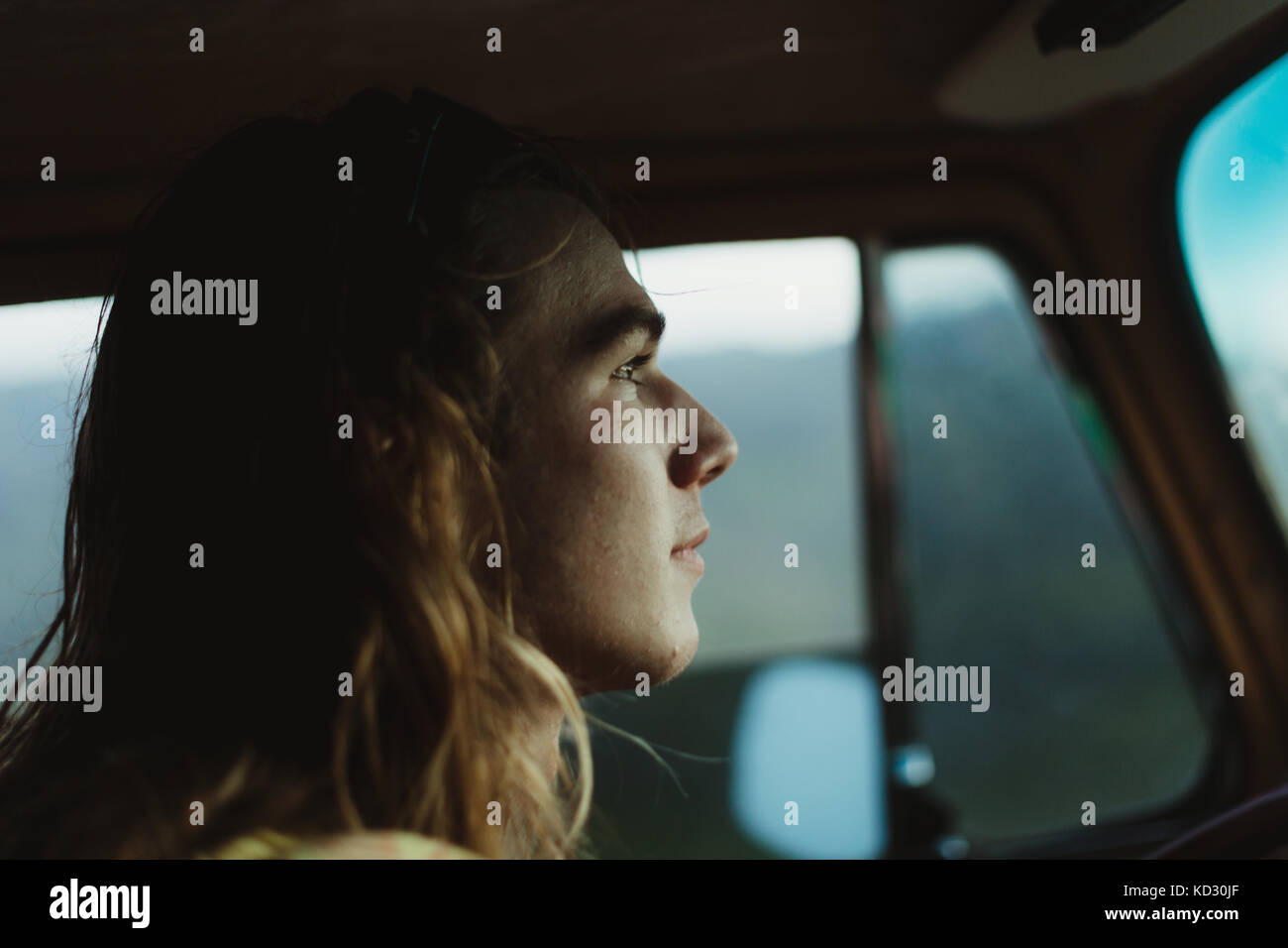 Tête de jeune homme aux cheveux longs au volant Banque D'Images