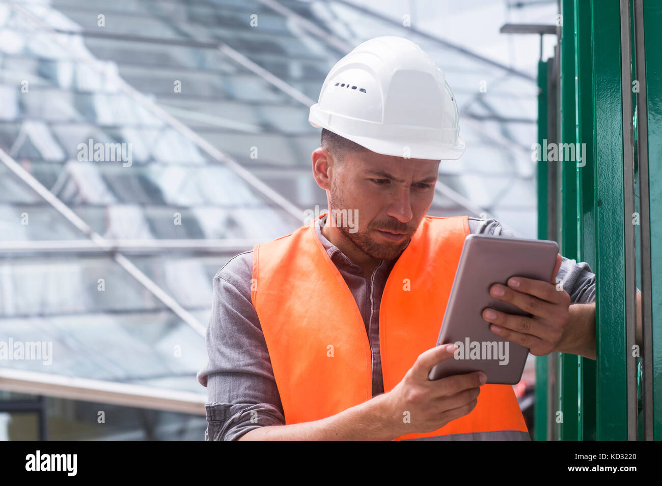 Man wearing hard hat high viz using digital tablet Banque D'Images