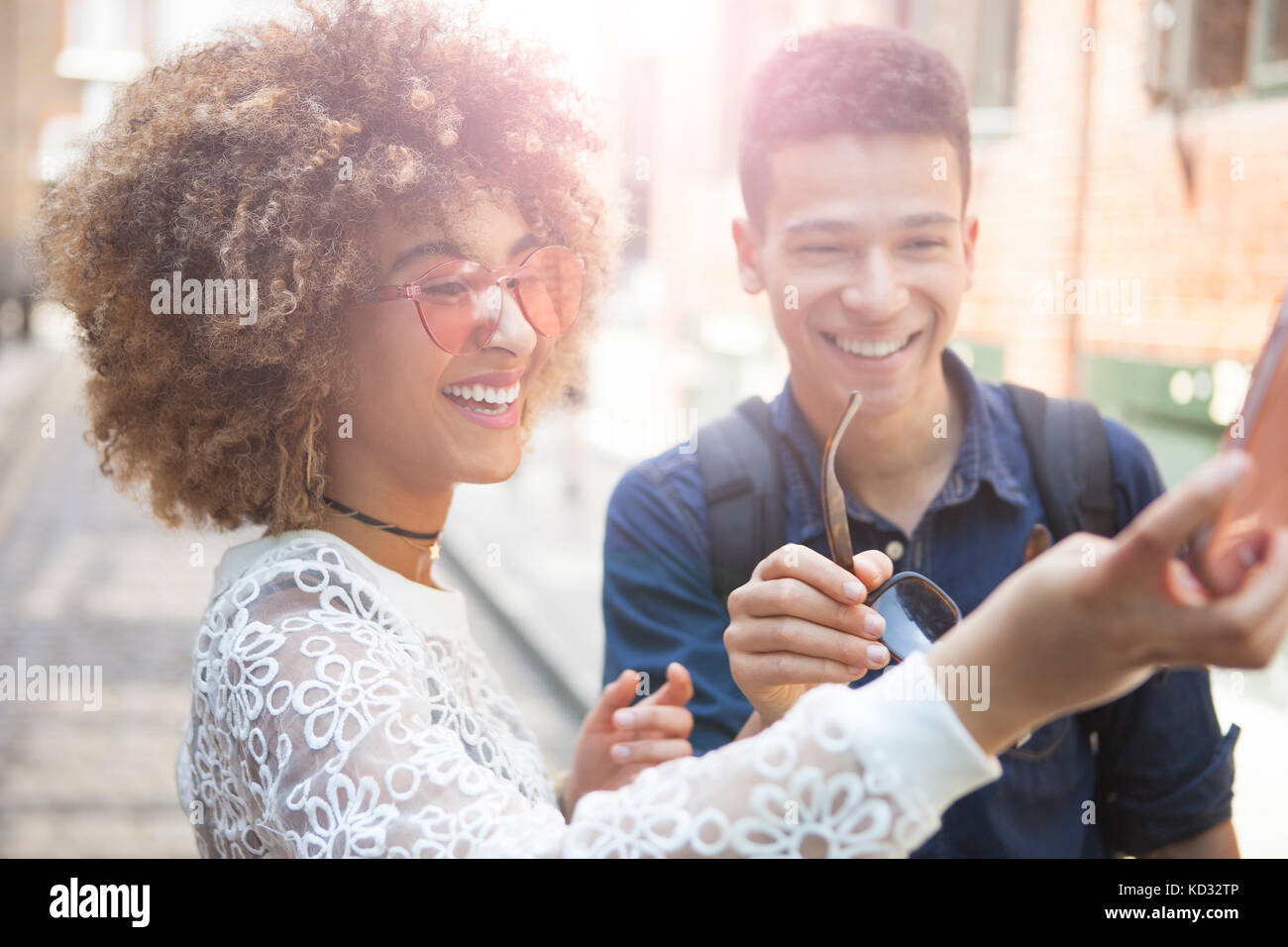 Jeune homme et femme à l'extérieur, en tenant, using smartphone selfies Banque D'Images