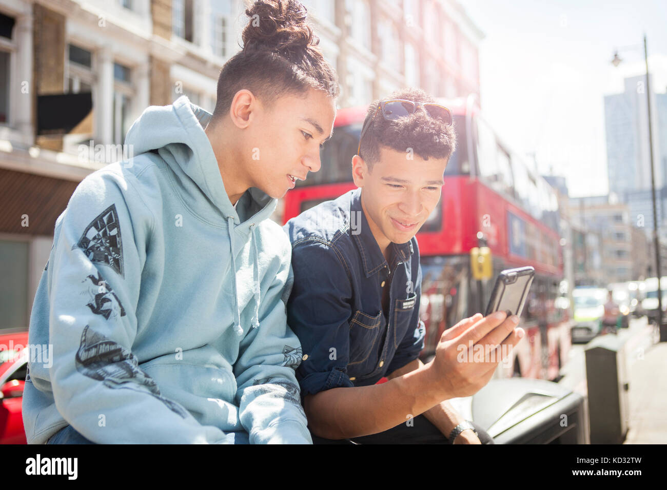 Deux jeunes hommes à l'extérieur, looking at smartphone Banque D'Images