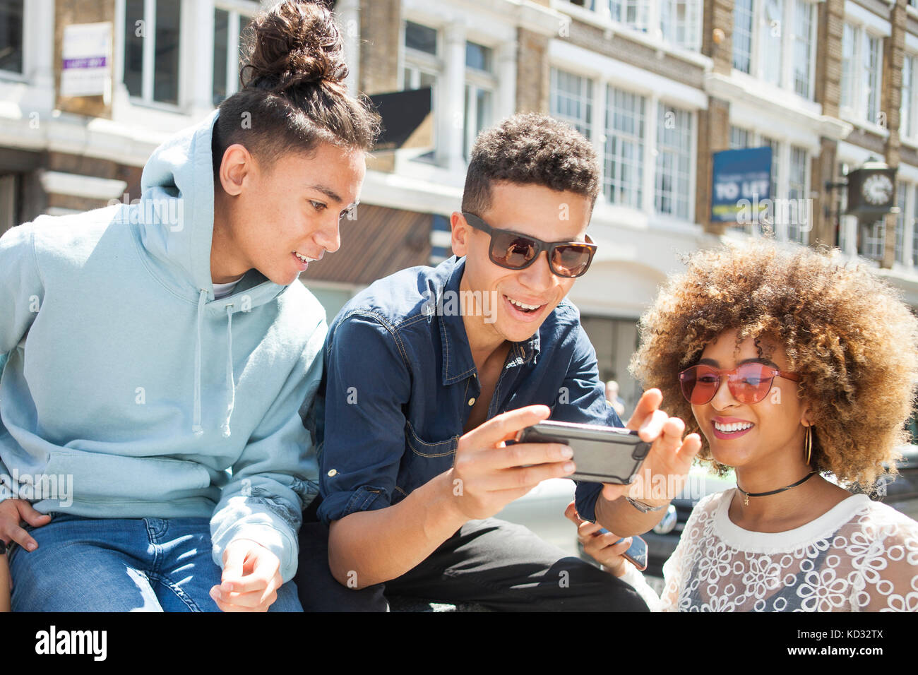 Trois jeunes amis à l'extérieur, looking at smartphone Banque D'Images
