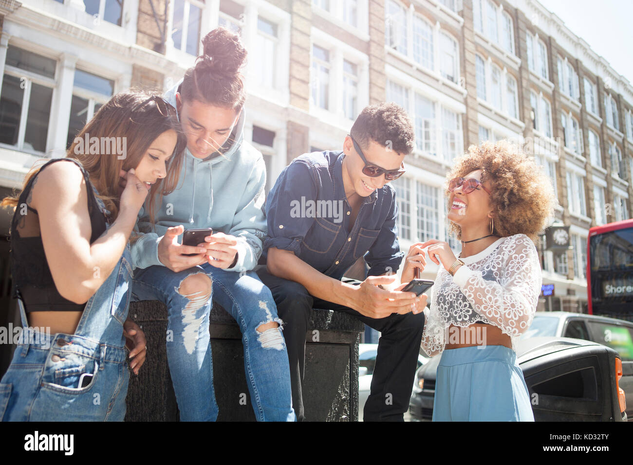 Quatre jeunes amis à l'extérieur, looking at smartphone Banque D'Images