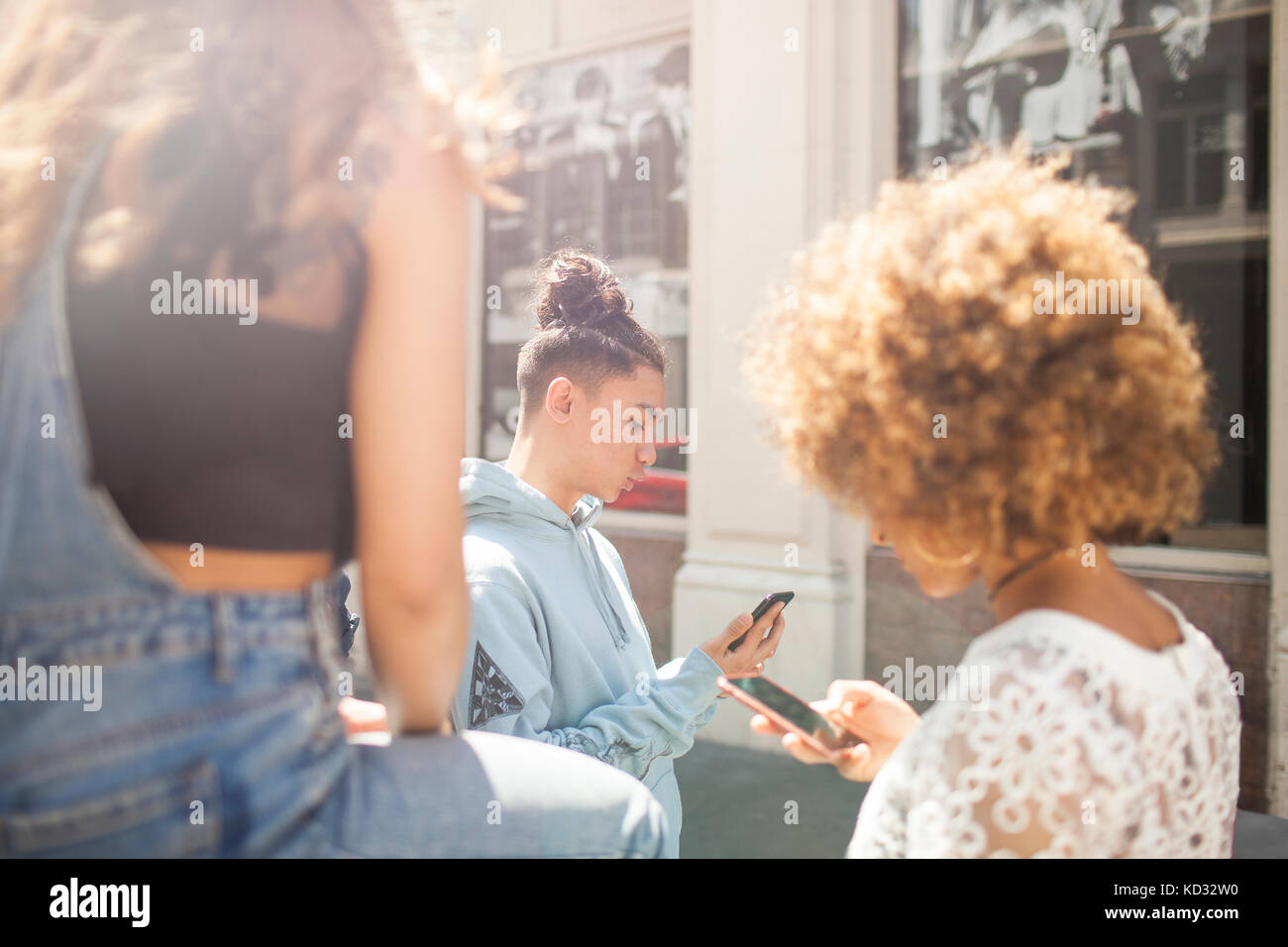 Trois jeunes amis à l'extérieur, à la recherche de téléphones intelligents Banque D'Images