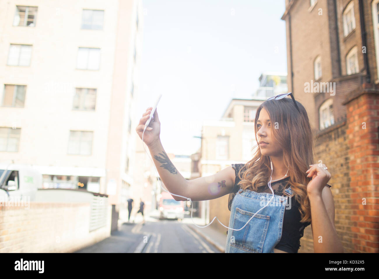 Jeune femme à l'extérieur, en tenant, using smartphone selfies Banque D'Images