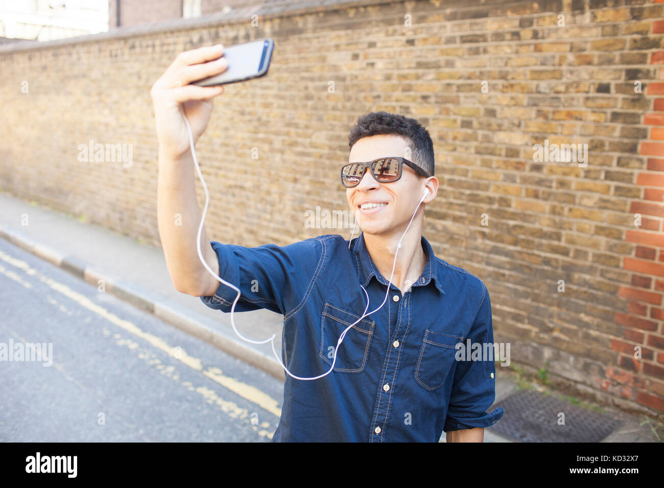 Jeune homme à l'extérieur, en tenant, à l'aide de téléphone intelligent selfies Banque D'Images