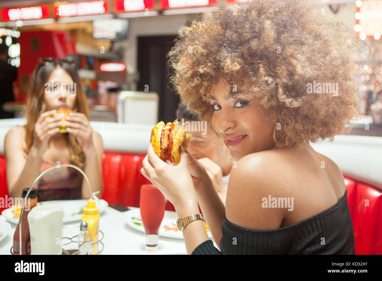 Trois jeunes amis, assis à manger, manger des hamburgers Banque D'Images