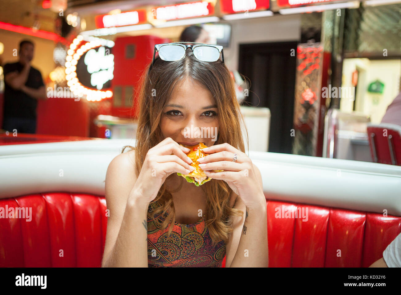 Portrait of young woman sitting in diner, eating sandwich Banque D'Images