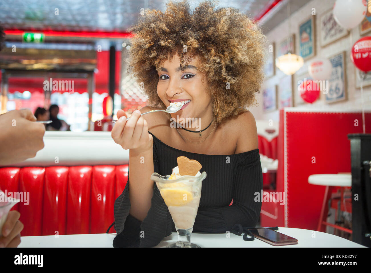 Portrait de jeune femme assise dans la salle à manger, manger des glaces dessert, smiling Banque D'Images