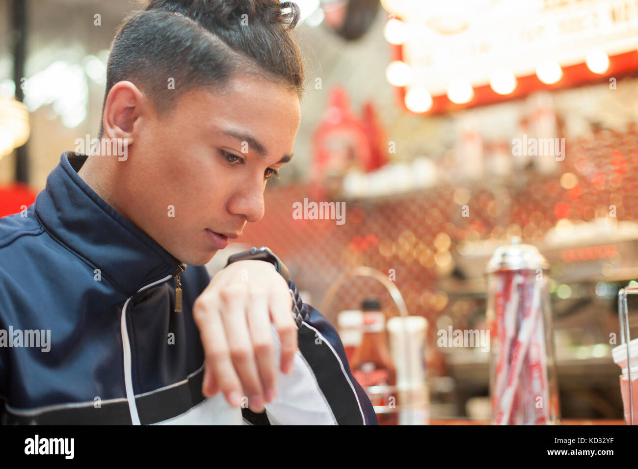 Jeune homme assis dans la salle à manger, parler en smartwatch Banque D'Images