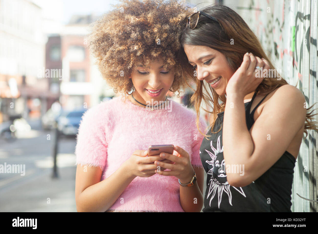 Deux jeunes femmes en rue, looking at smartphone Banque D'Images