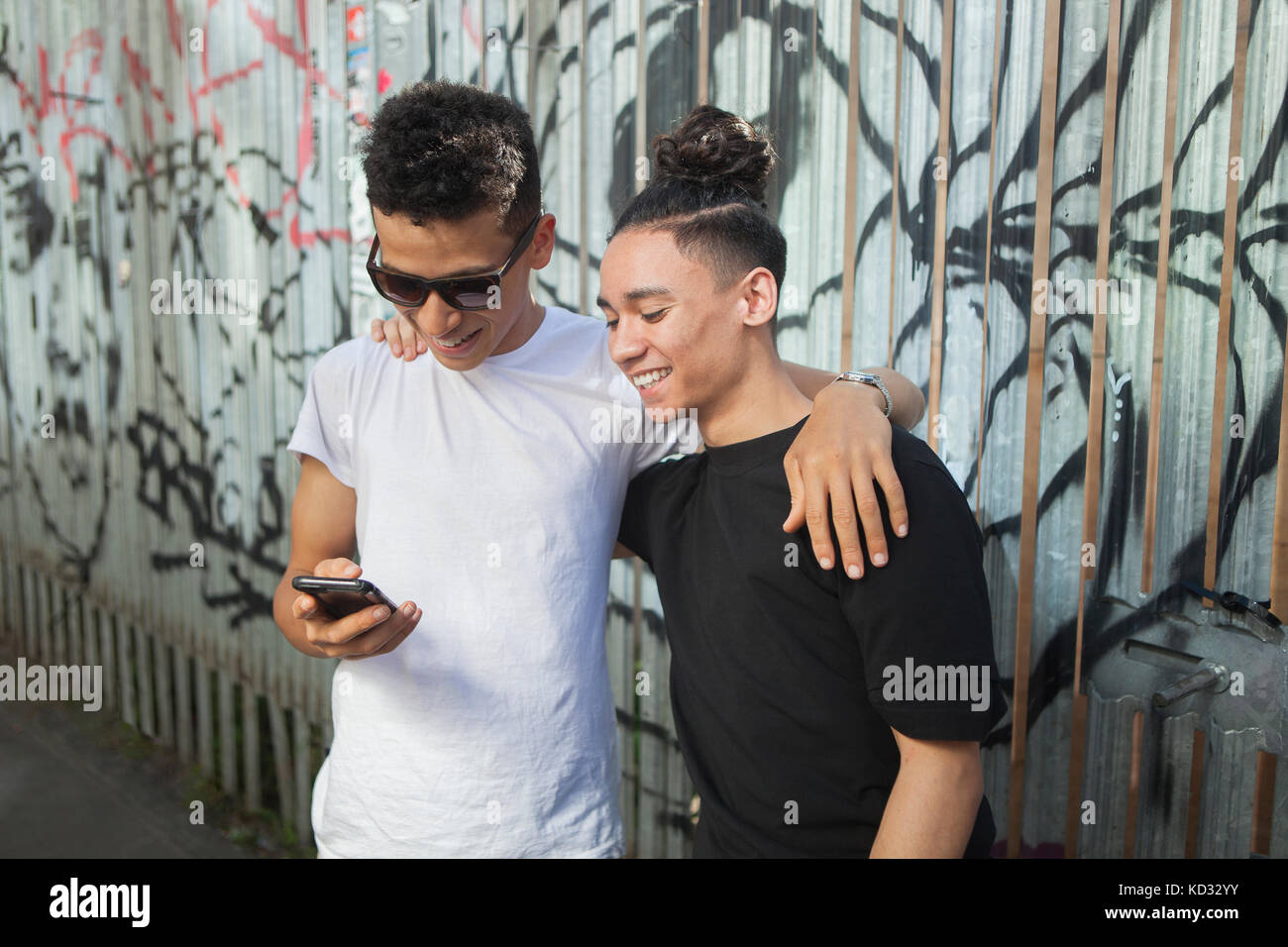 Deux jeunes hommes à la rue, looking at smartphone Banque D'Images