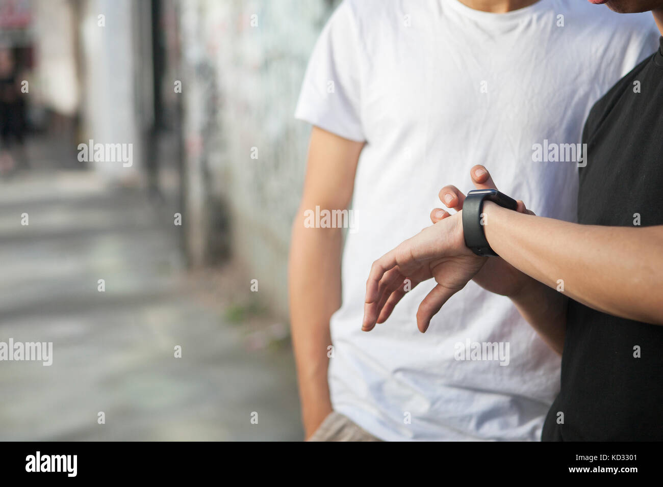 Deux jeunes hommes à la rue, à la section intermédiaire, à smartwatch Banque D'Images