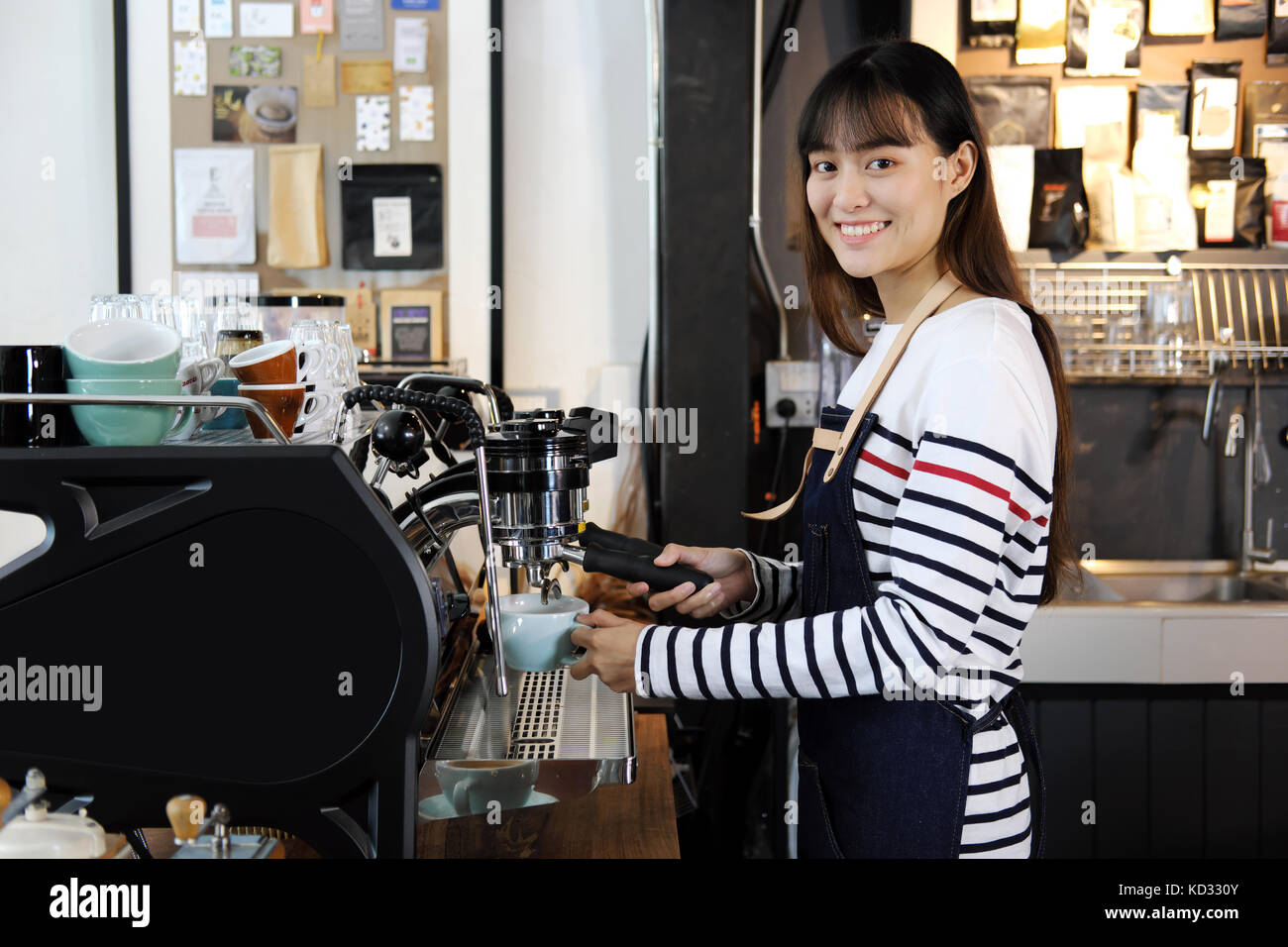 Portrait of smiling asian barista la préparation de cappuccino avec machine à café. café restaurant service, propriétaire de petite entreprise, l'industrie alimentaire et des boissons con Banque D'Images