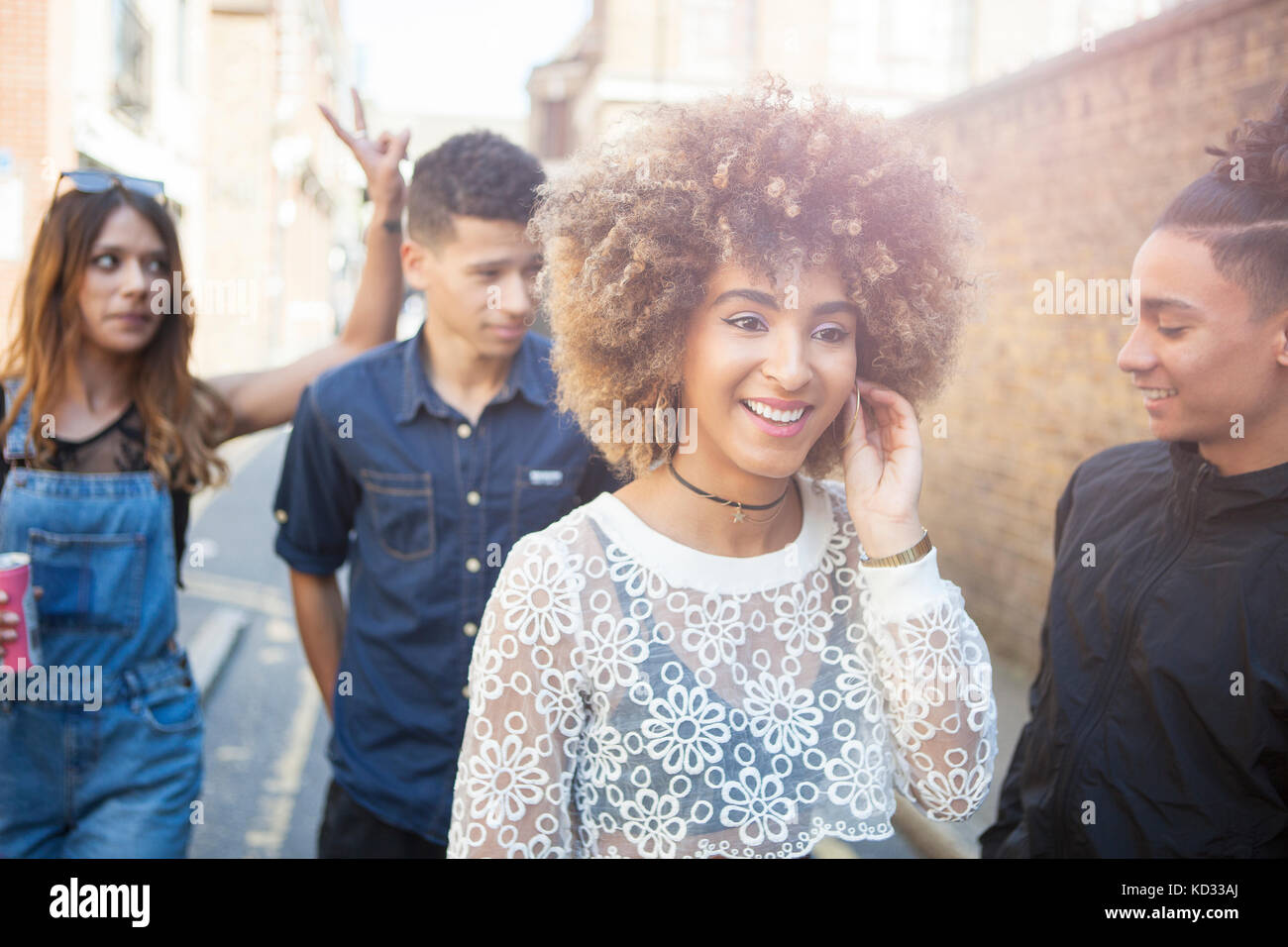 Quatre jeunes amis walking outdoors, smiling Banque D'Images