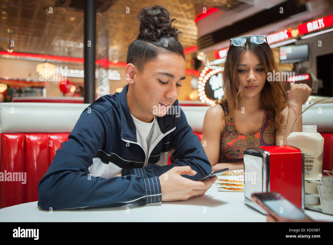 Jeune couple, assis dans une guinguette, young man looking at smartphone, femme avec expression d'ennui Banque D'Images