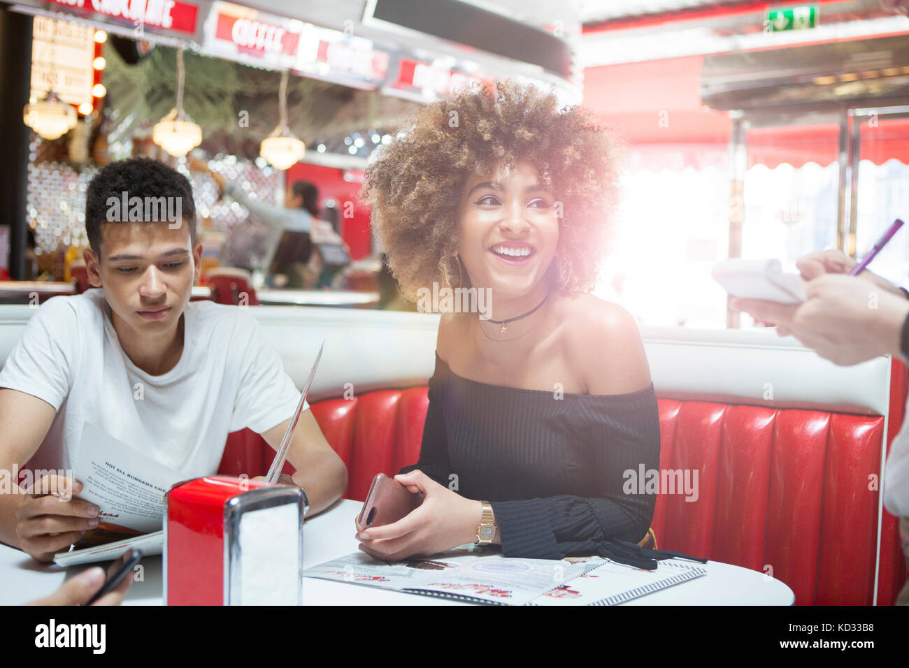 Young couple sitting in diner donnant vue de serveuse Banque D'Images
