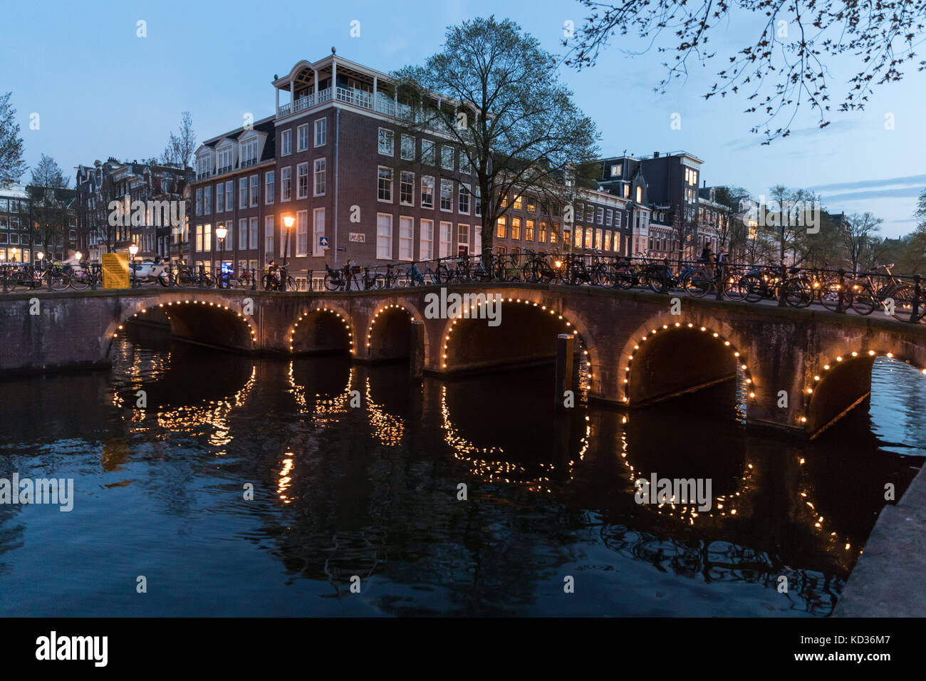 Arches du pont illuminé reflétée dans le canal Herengracht à Amsterdam Banque D'Images