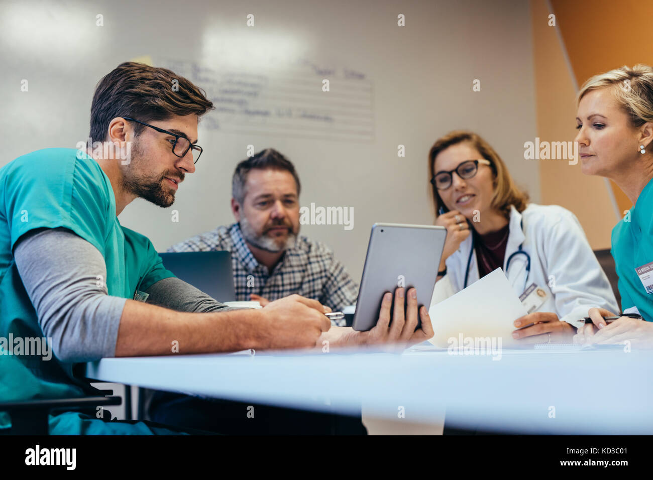 Le personnel médical de l'équipe avoir matin réunion en salle du Conseil. Médecins et infirmières looking at digital tablet. Banque D'Images