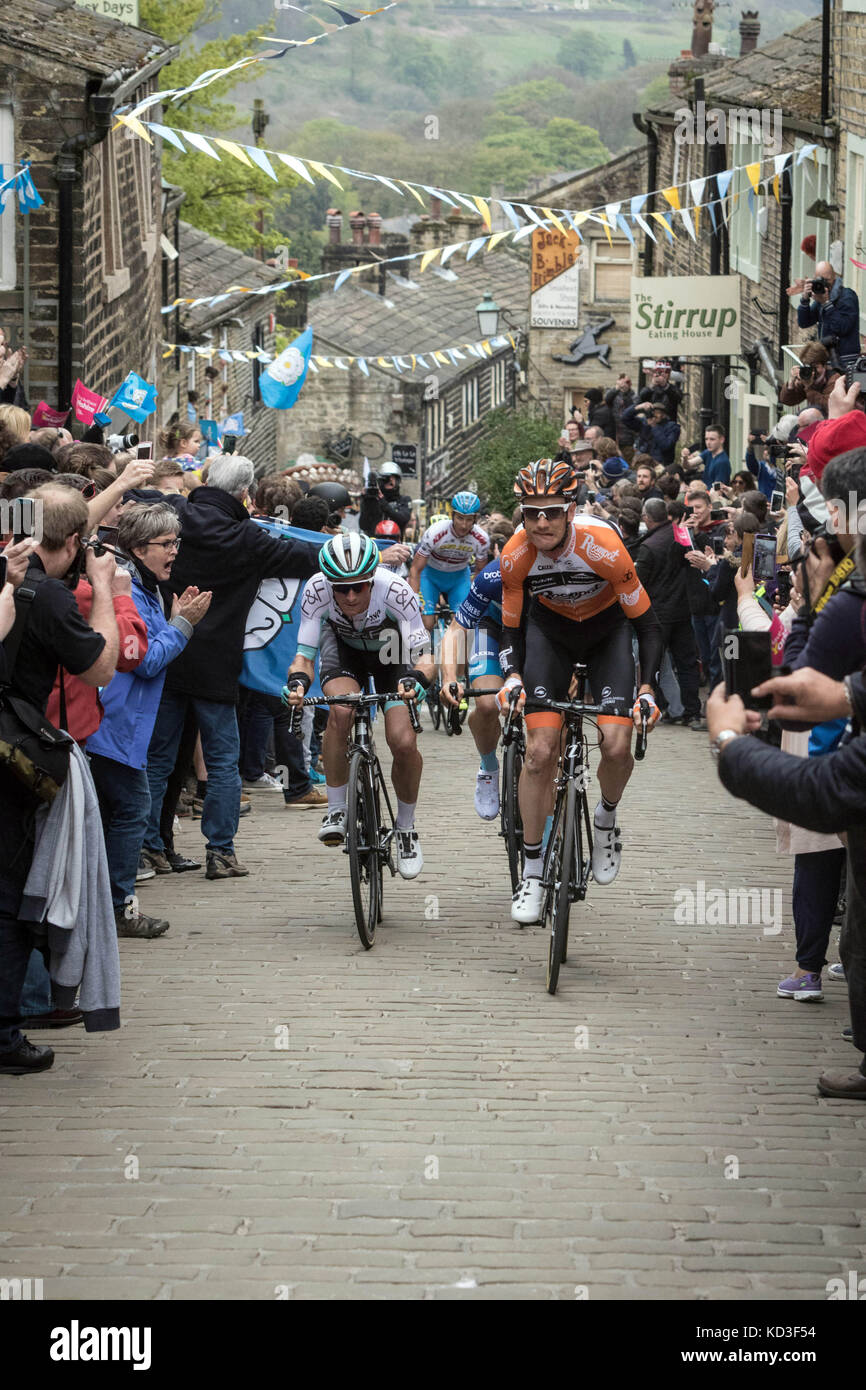 Les coureurs du Tour de Yorkshire monter la rue Main à Haworth, West Yorkshire Banque D'Images