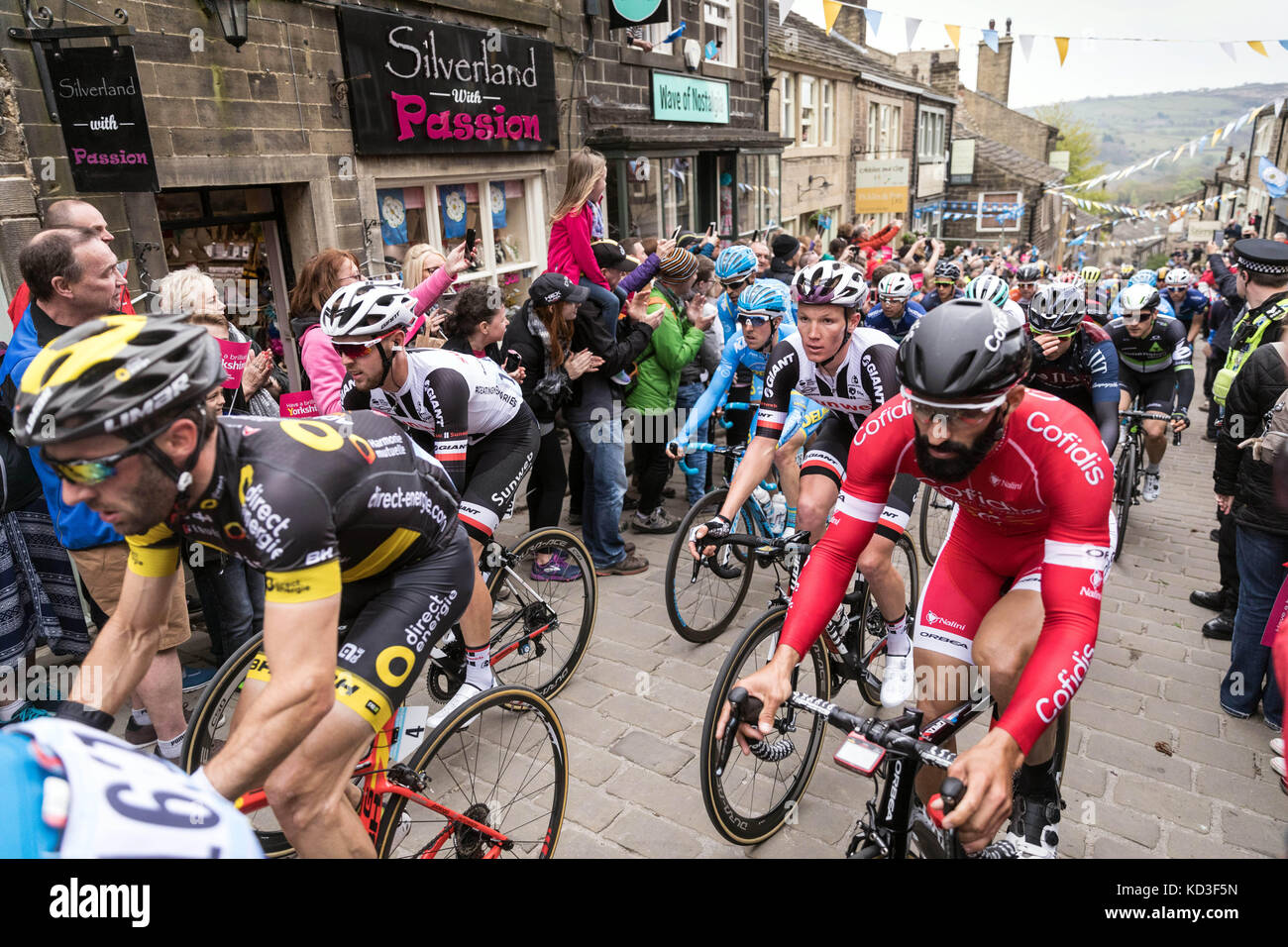 Les coureurs du Tour de Yorkshire monter la rue Main à Haworth, West Yorkshire Banque D'Images
