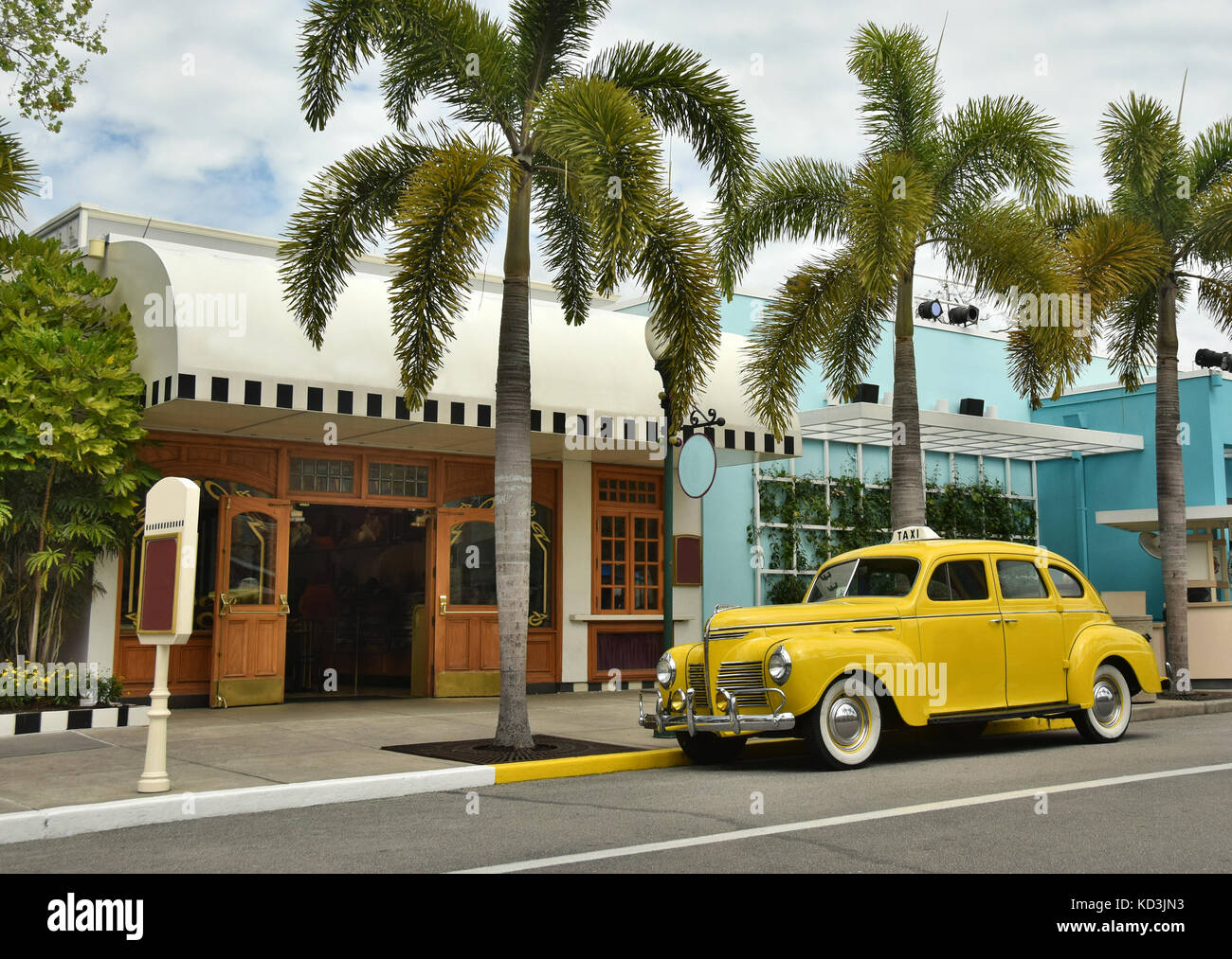 Vieux taxi jaune sur une rue bordée de palmiers Banque D'Images