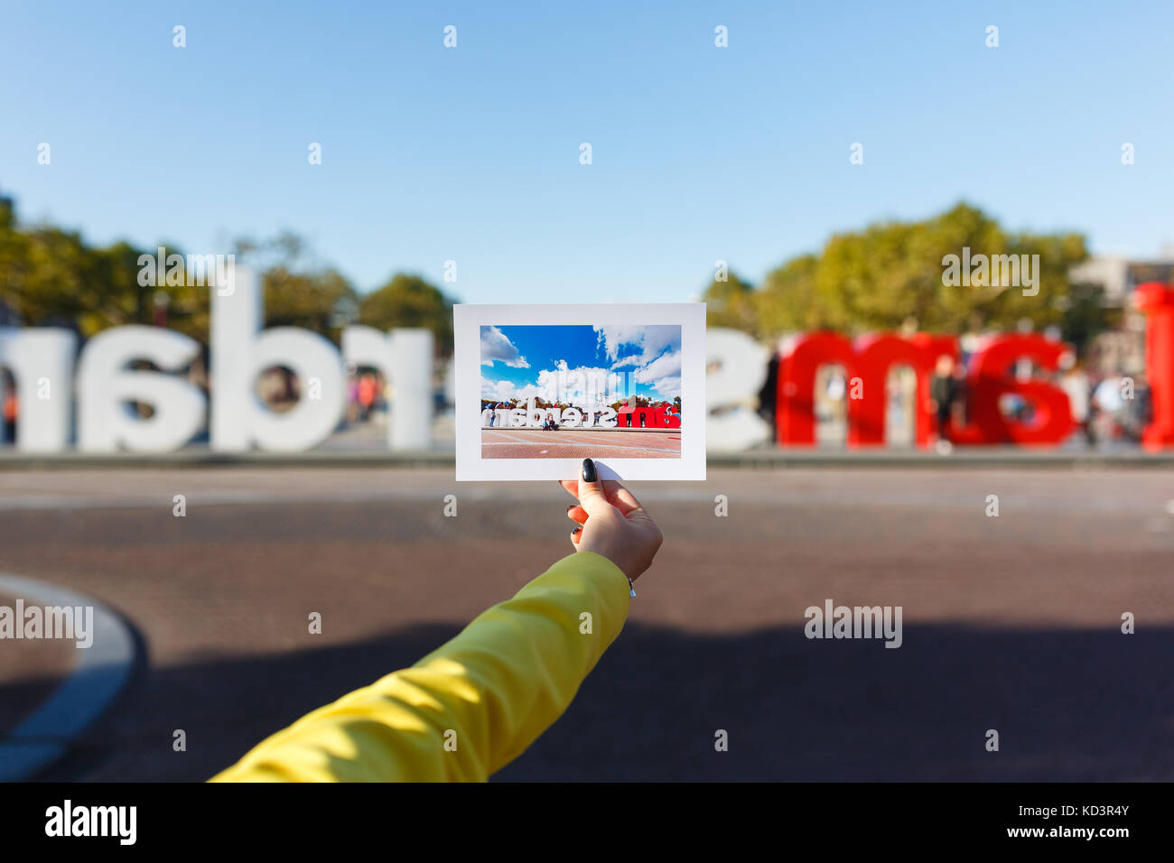 Femme main qui tient une photo de sites i amsterdam dans l'arrière-plan cette vue Banque D'Images