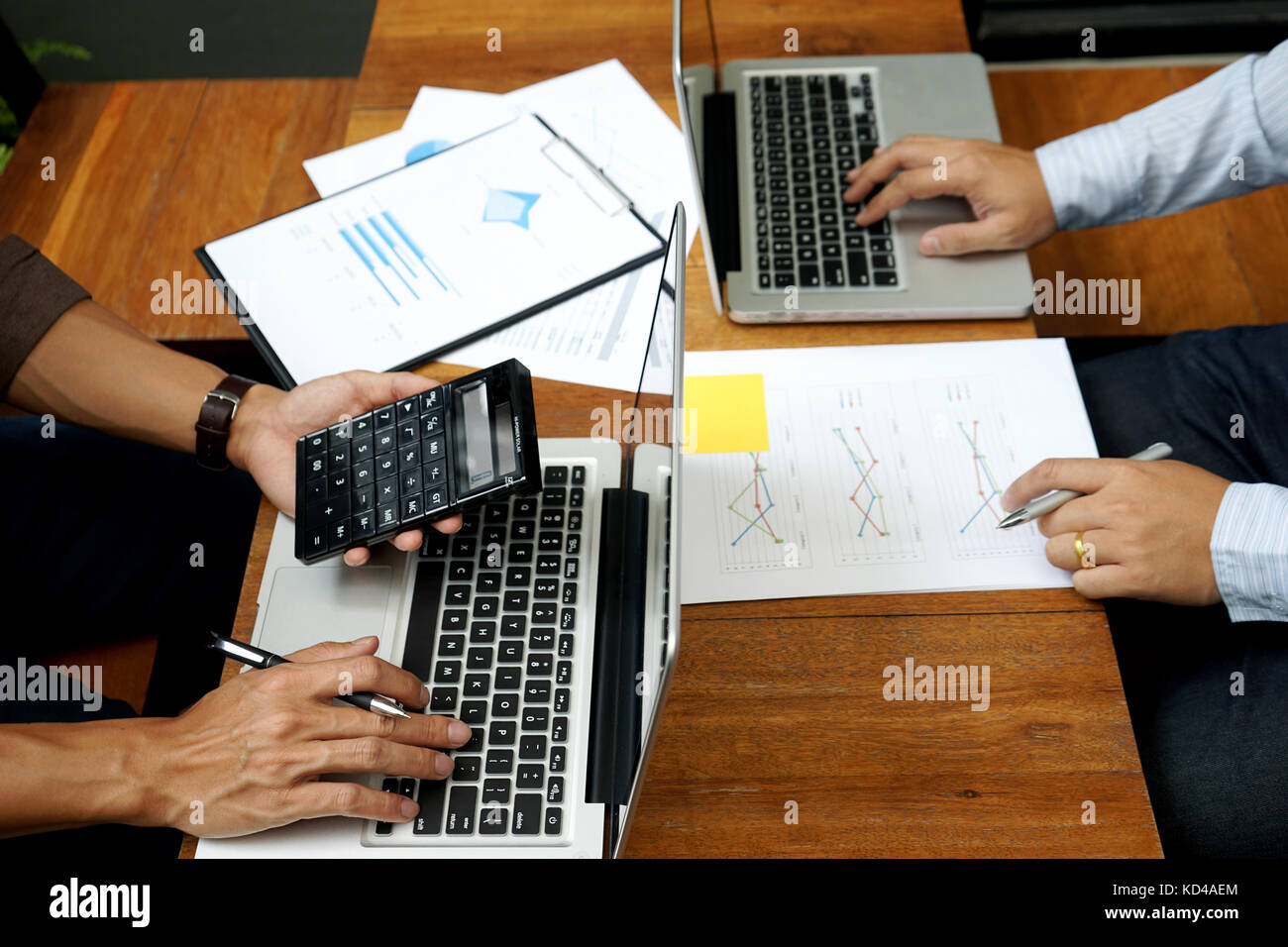 Deux man utilisent l'ordinateur et de l'analyse graphique papier sur bois table plus copy space Banque D'Images