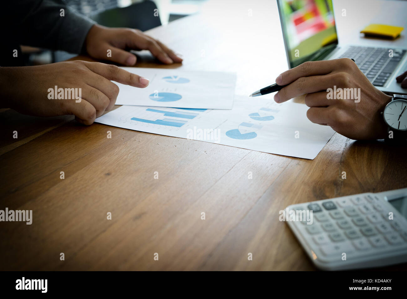 Deux man utilisent l'ordinateur et de l'analyse graphique papier sur bois table plus copy space Banque D'Images