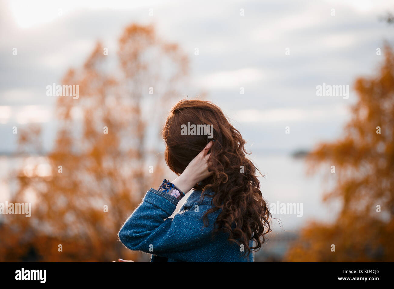 Cheveux bouclés belle young caucasian girl outdoors wearing Blue Coat, posing in autumn park Banque D'Images
