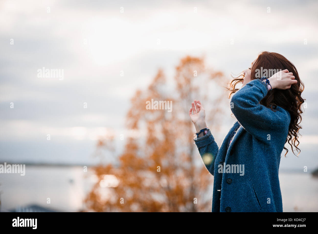 Cheveux bouclés belle young caucasian girl outdoors wearing Blue Coat, posing in autumn park Banque D'Images